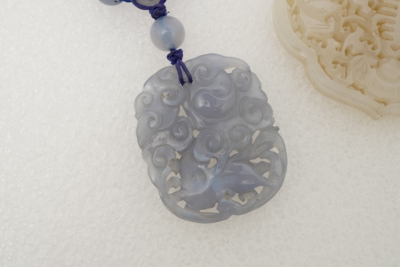 A Chinese jade ‘spirit lock’ plaque, a jadeite bead necklace and a blue quartz bead necklace, 20th century